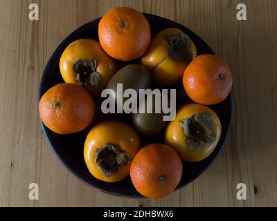 Kiwis, kakis and tangerines in a bowl Stock Photo