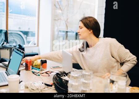 Junge weibliche Computerprogrammiererin, die beim Sitzen am Schreibtisch arbeitet Kleines Kreativbüro Stockfoto