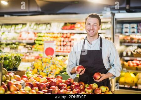 Porträt eines lächelnden, reifen Besitzers, der am Apfelstand steht Lebensmittelgeschäft Stockfoto