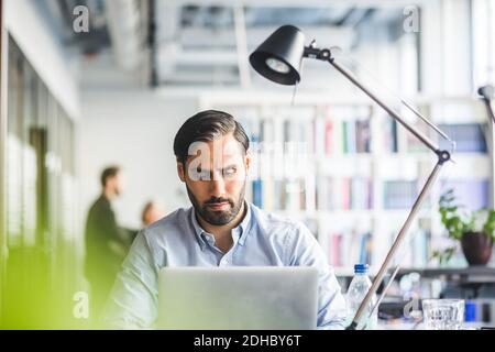 Kreative Geschäftsmann mit Laptop im Büro Stockfoto