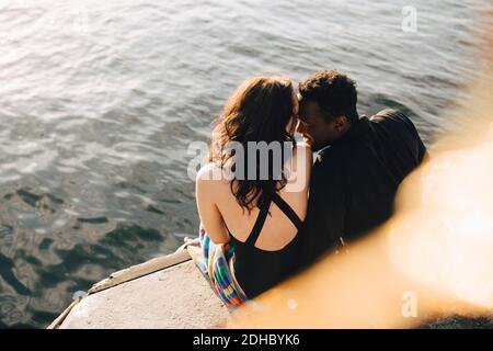 Blick aus der Höhe des anhänglichen Paares, das auf dem Steg sitzt see Stockfoto