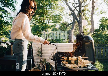 Frau, die im Sommer auf dem Hof gegrillt wird Stockfoto