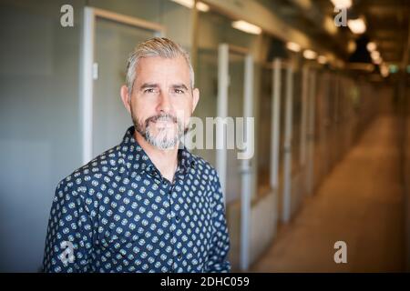 Portrait des selbstbewussten reifen Geschäftsmann stehen auf Korridor in kreativ Büro Stockfoto