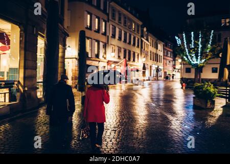 Straßburg, Frankreich - 4. Dezember 2020: Leere Straße mit geschlossenen Geschäften während des Schwarzen Freitags mit einem erwachsenen Paar mit einem Regenschirm an einem regnerischen Tag Stockfoto