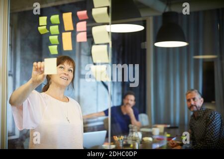 Kreative Geschäftsleute Brainstorming Ideen über Klebenoten in Board Zimmer Stockfoto