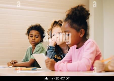 Schülerinnen und Schüler, die im Klassenzimmer digitale Tablets betrachten Stockfoto