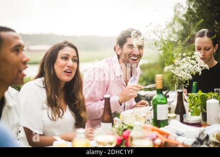 Glückliche Freunde genießen Abendessen am Tisch im Hinterhof während der Party Stockfoto