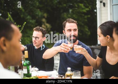 Mann und Frau toasten Getränke während genießen Abendessen Party mit Freunde im Hinterhof Stockfoto