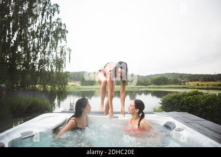 Weibliche Freunde genießen im Whirlpool während Wochenende Kurzurlaub gegen Der Himmel ist klar Stockfoto