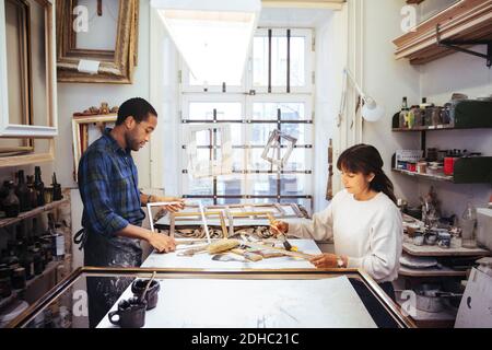 Männlicher Handwerker, der Rahmen mit weiblicher Mitarbeiterin an der Werkbank macht Speichern Stockfoto