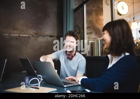Fröhliche weibliche und männliche Unternehmer diskutieren über Laptop am Schreibtisch Im Büro Stockfoto