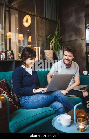 Lächelnd multi-ethnischen männlichen und weiblichen Unternehmer diskutieren über Laptop auf Sofa im Büro Stockfoto