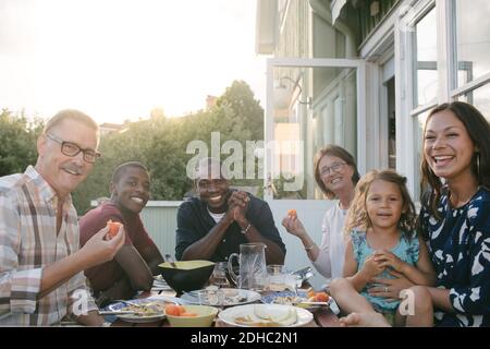 Porträt einer lächelnden Familie mit mehreren Generationen, die am Tisch zu Mittag essen Veranda Stockfoto