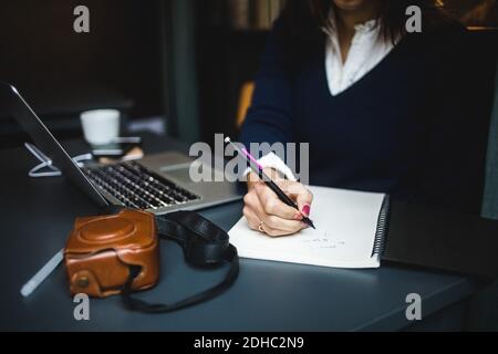 Mittelteil einer Geschäftsfrau, die an der Rezeption Tagebuch schrieb Stockfoto