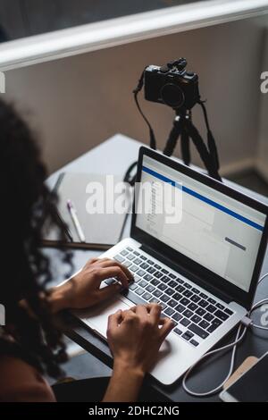 High-Angle-Ansicht der jungen weiblichen Influencer vlogging während der Verwendung Laptop am Schreibtisch im kreativen Büro Stockfoto