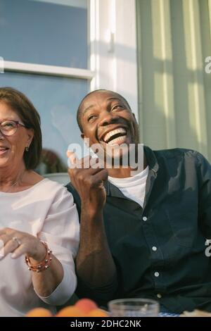 Glückliche ältere Frau, die bei einem Mann auf der Veranda sitzt Stockfoto