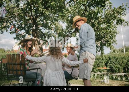 Familie applaudiert beim Blick auf ältere Mann und Mädchen tanzen Während Gartenparty Stockfoto