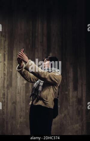 Junge Frau puckering während der Aufnahme Selfie mit Handy gegen Mauer in der U-Bahn Stockfoto