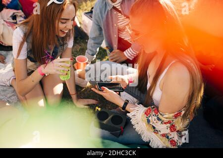 Aus dem hohen Winkel betrachten Sie Freunde, die während des Gesprächs über das Mobiltelefon sprechen Genießen auf Musikfestival Stockfoto