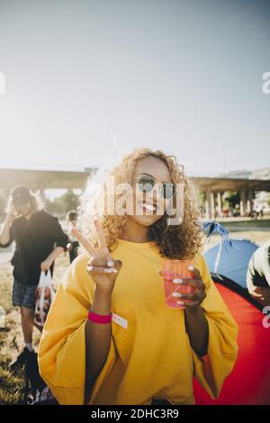 Porträt einer lächelnden Frau, die gestikuliert, während sie in Musik einen Drink genießt festival Stockfoto