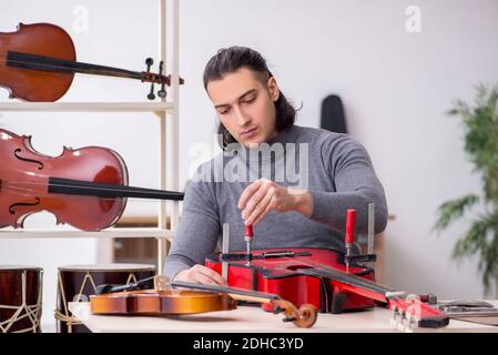 Junger männlicher Mechaniker, der Gitarre repariert Stockfoto