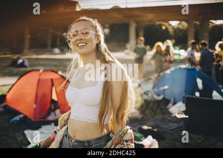 Porträt einer lächelnden jungen Frau, die eine Sonnenbrille trägt und bei Musik steht festival Stockfoto