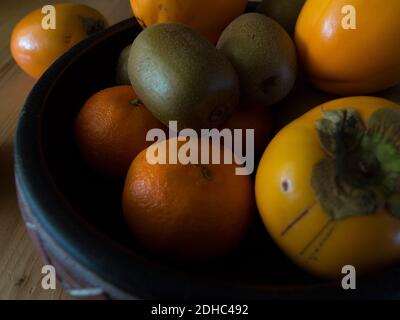 Kiwis, kakis and tangerines in a bowl Stock Photo