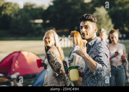 Portrait von lächelnden Mann gesturing während genießen mit Freunden an Konzert Stockfoto