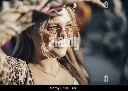 Nahaufnahme einer lächelnden Frau, die die Augen umschlingende, während sie in die Ferne schaute Sommer Stockfoto