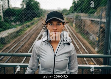 Porträt einer selbstbewussten Sportlerin, die auf der Brücke gegen Geländer steht Stockfoto
