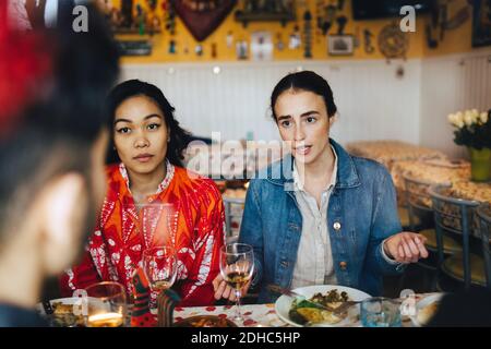 Junge Frauen im Gespräch mit männlichen Freund während der Dinner-Party bei Restaurant Stockfoto