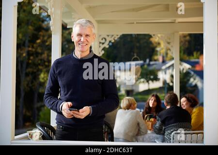 Portrait von zuversichtlich lächelnd reifen Mann auf der Veranda mit stehen Freunde im Hintergrund Stockfoto