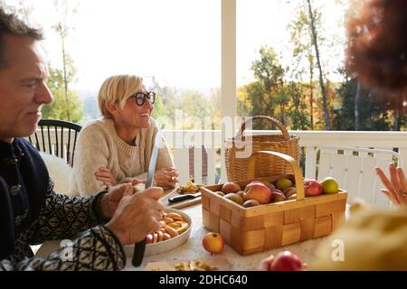 Reifer Mann schneiden Apfel, während fröhliche Frau wegschauen auf Veranda Stockfoto