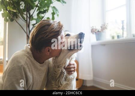 Nahaufnahme eines pensionierten älteren Mannes, der Retriever küsst, während er ansitzt Zu Hause Stockfoto