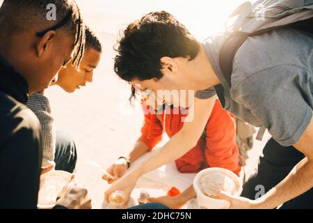 Freunde essen Essen zum Mitnehmen auf der Promenade in der Stadt während Sonniger Tag Stockfoto