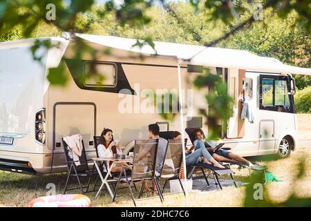 Familie entspannen auf Stühlen außerhalb Wohnmobil auf dem Campingplatz während Sommerurlaub Stockfoto