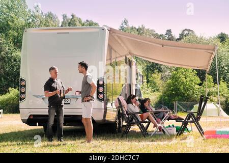 Älterer Mann, der mit dem Sohn sprach, während die Familie sich draußen im Van erholte Auf dem Campingplatz Stockfoto
