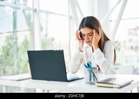 Gestresste müde Geschäftsfrau sitzt an ihrem Schreibtisch in modernen Büro Stockfoto