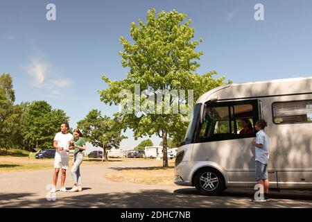 Teenager Junge steht von der Mutter im Wohnmobil, während Vater Und Tochter beim Lesen der Karte auf der Straße Stockfoto