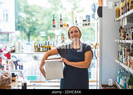 Portrait von selbstbewussten weiblichen Besitzer mit Karton im Deli Stockfoto