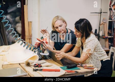 Polsterinnen diskutieren über Laptop an der Werkbank in der Werkstatt Stockfoto