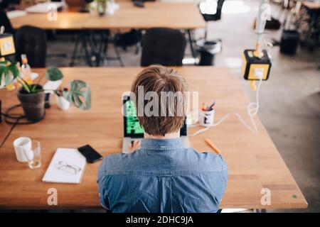 Rückansicht des Computerprogrammierers, der am Schreibtisch arbeitet, in kreativem Büro Stockfoto