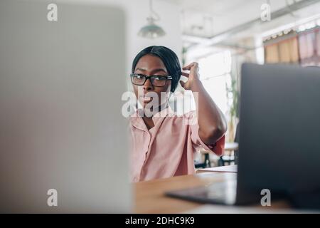 Verwirrt Geschäftsfrau Blick auf Laptop, während sitzen am Schreibtisch in Kreatives Büro Stockfoto