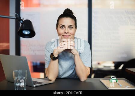 Porträt einer selbstbewussten kreativen Geschäftsfrau, die im Büro am Schreibtisch sitzt Stockfoto