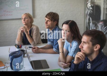 Kreative Geschäftsleute, die im Konferenzraum sitzen, hören zu Stockfoto