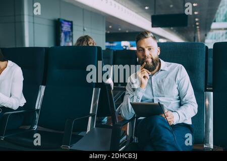 Porträt des Geschäftsmannes sitzt mit digitalen Tablet im Wartezimmer Am Abflugbereich des Flughafens Stockfoto