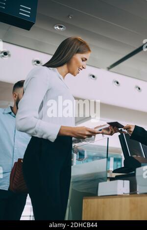 Man hatte einen niedrigen Blick auf die lächelnde junge Geschäftsfrau, die beim Einchecken war flughafen Stockfoto