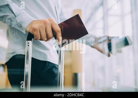 Mittelteil des Geschäftsmannes mit Pass am Flughafen Stockfoto