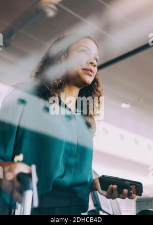 Aus der Sicht der Geschäftsfrau, die ihr Smartphone im Stehen hält Am Flughafen Stockfoto