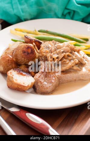 Thicvk schneiden Schweinekotelett mit gebratenen Kartoffeln, Pilzen und Bohnen Stockfoto